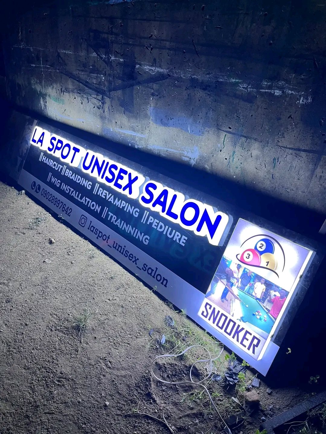 High-impact non-illuminated dimensional 3D storefront sign with raised blue-and-white acrylic block lettering and photo-graphic sub-panel for a commercial lounge in Masaka, Uganda.